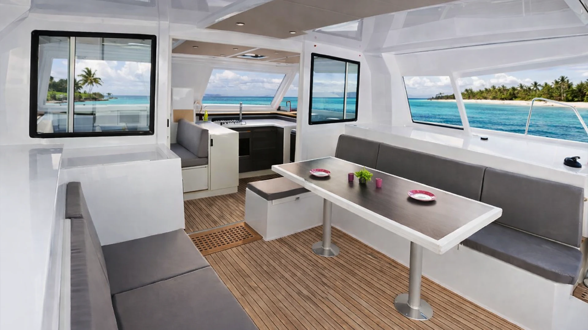 Salon extérieur lumineux d’un catamaran privatisé en Guadeloupe, avec table à manger, banquettes confortables et vue sur un lagon turquoise lors d’une croisière ou excursion à la journée