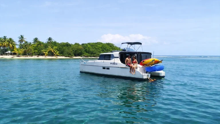 Excursion en bateau dans le Grand Cul-de-Sac Marin en Guadeloupe, couple profitant d’un catamaran au mouillage près d’un îlet tropical aux eaux turquoise.