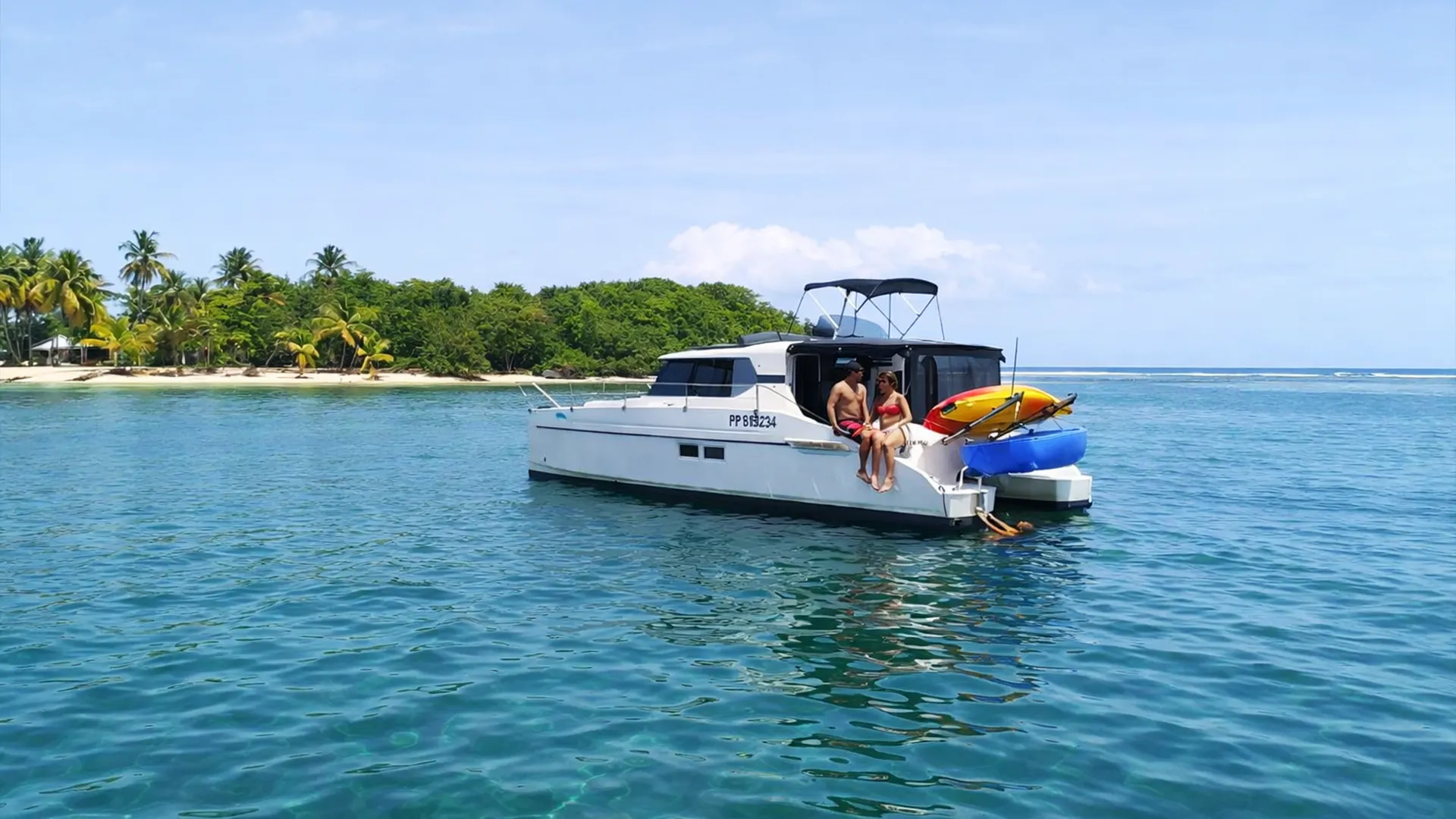 Excursion en bateau dans le Grand Cul-de-Sac Marin en Guadeloupe, couple profitant d’un catamaran au mouillage près d’un îlet tropical aux eaux turquoise.