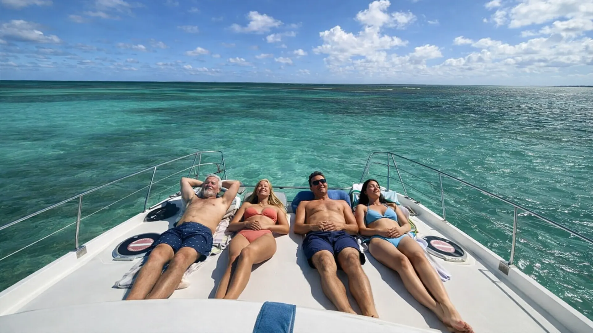 Excursion en bateau dans le Grand Cul-de-Sac Marin en Guadeloupe, passagers allongés à l’avant d’un catamaran profitant du soleil au-dessus d’un lagon turquoise.