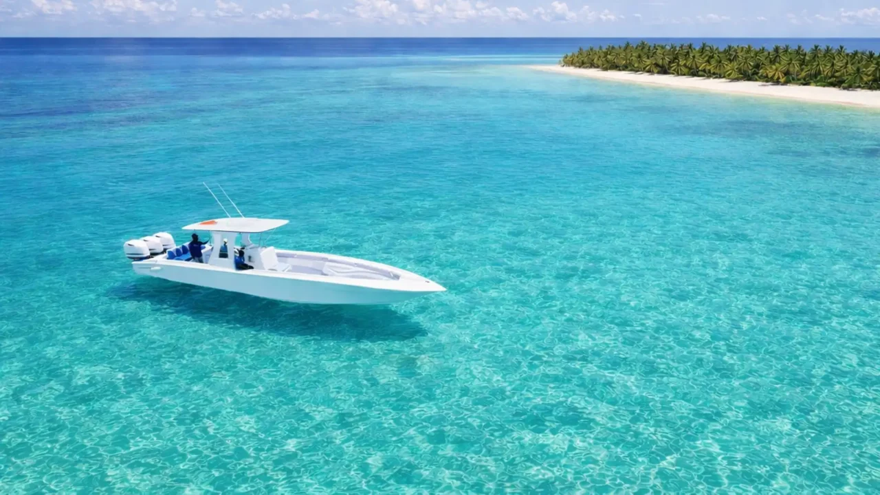 Speedboat naviguant sur des eaux turquoise lors d’une excursion en Guadeloupe, face à un îlot bordé de palmiers