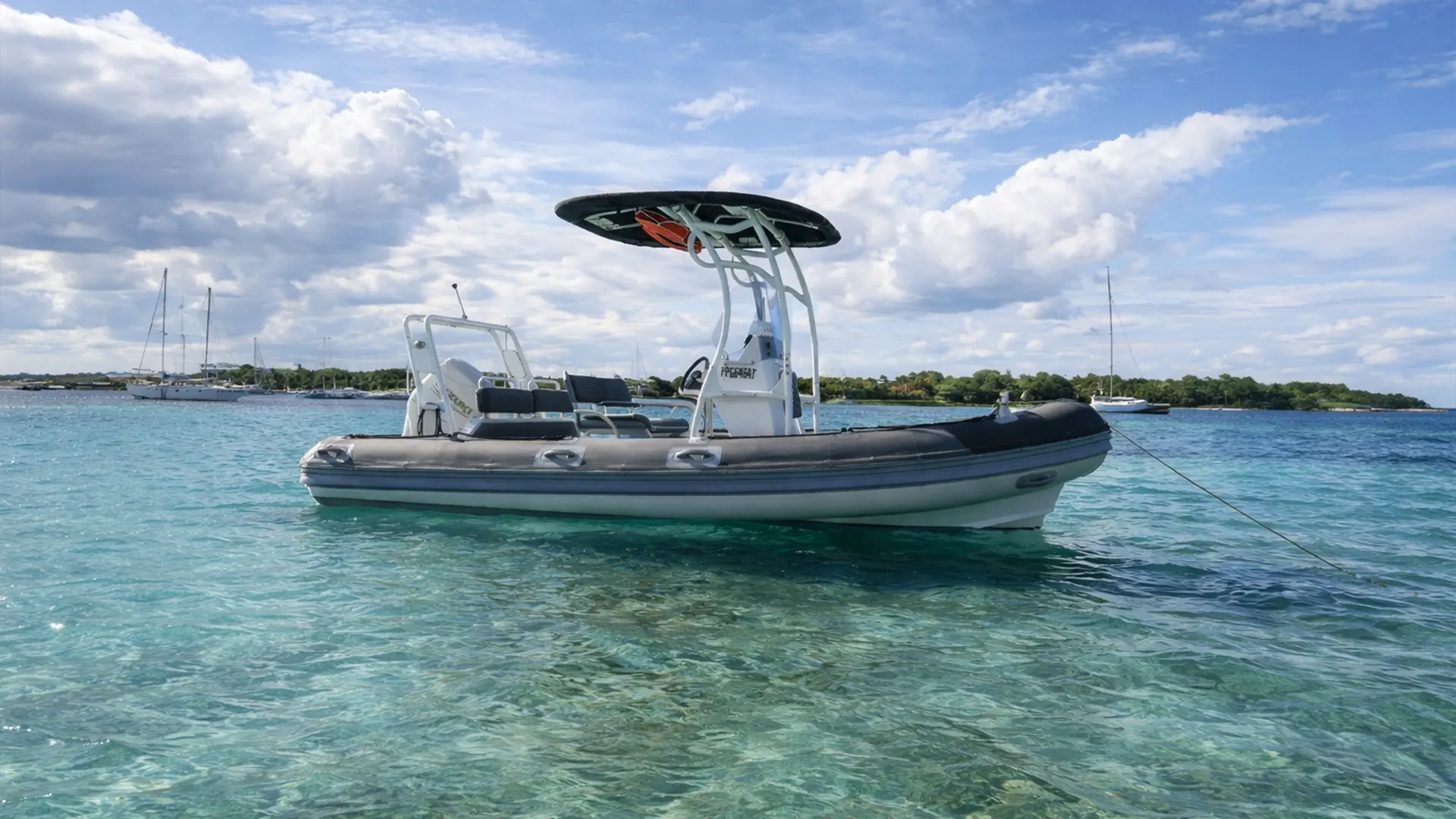 Bateau semi-rigide dans une eau turquoise en Guadeloupe avec lagon et voiliers à l’horizon
