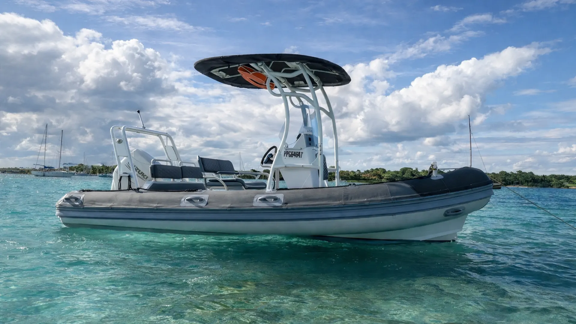Bateau semi-rigide dans une eau turquoise en Guadeloupe avec lagon et voiliers à l’horizon