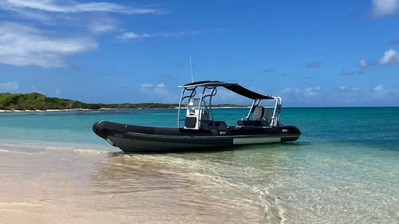 Bateau semi-rigide Highfield Patrol 760 posé sur une plage aux eaux turquoise en Guadeloupe pour explorer les îles et Petite-Terre