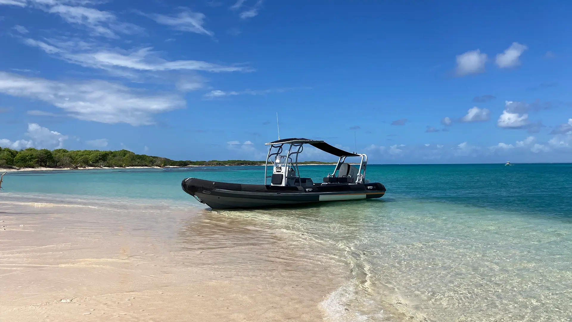 Bateau semi-rigide Highfield Patrol 760 posé sur une plage aux eaux turquoise en Guadeloupe pour explorer les îles et Petite-Terre