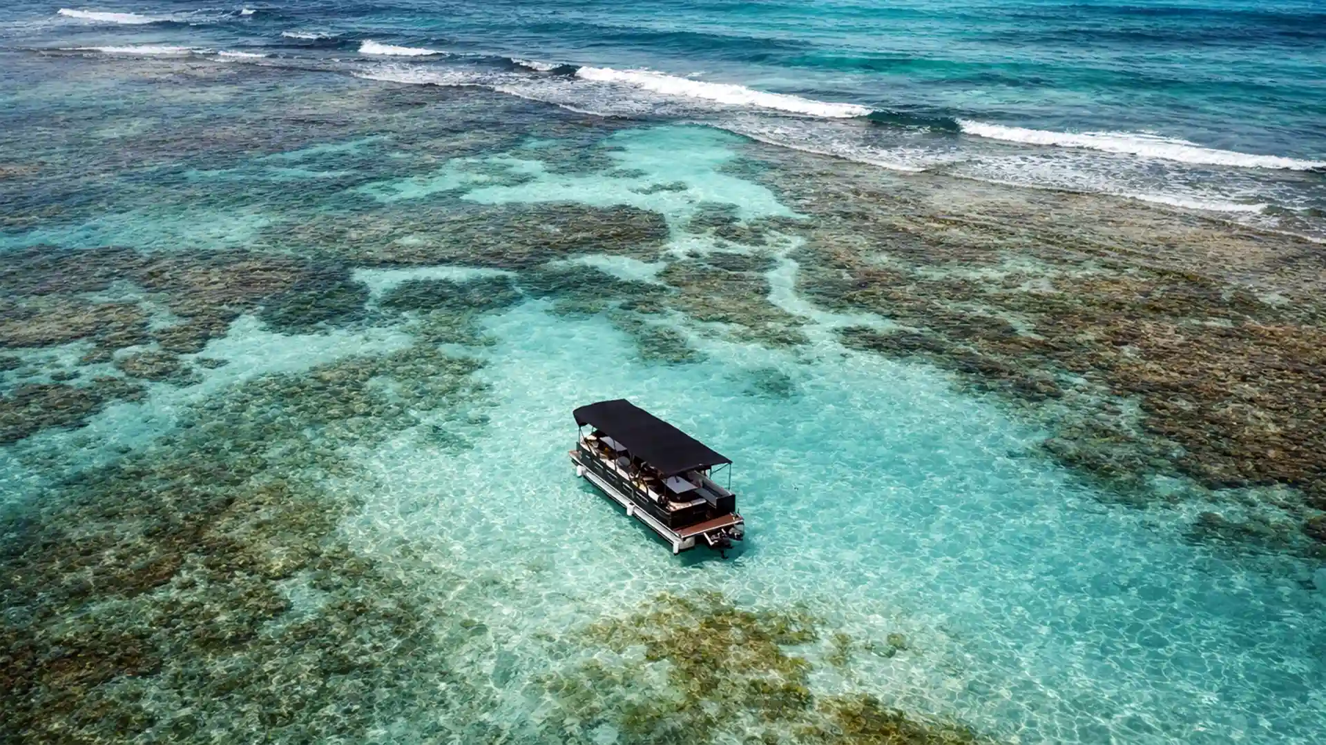 Lounge Boat en Guadeloupe à l'arrêt sur un lagon turquoise, bateau festif privé pour Boat Party et BBQ en mer